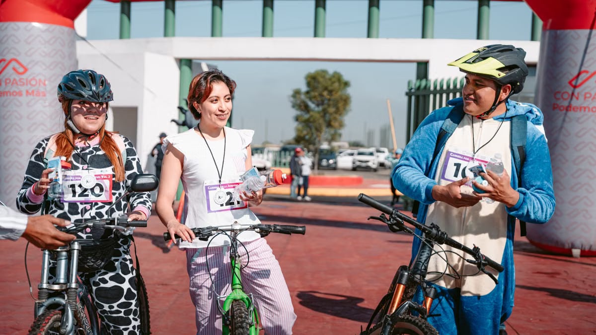 Three cyclists in costume celebrate the end of a race by the finish line arch outdoors.